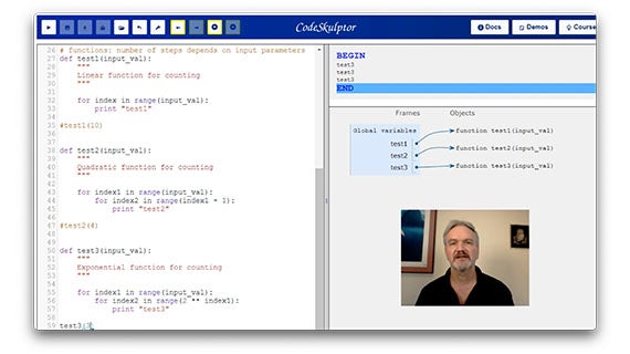 A man's face is visible on a computer screen, accompanied by another screen in a modern workspace.